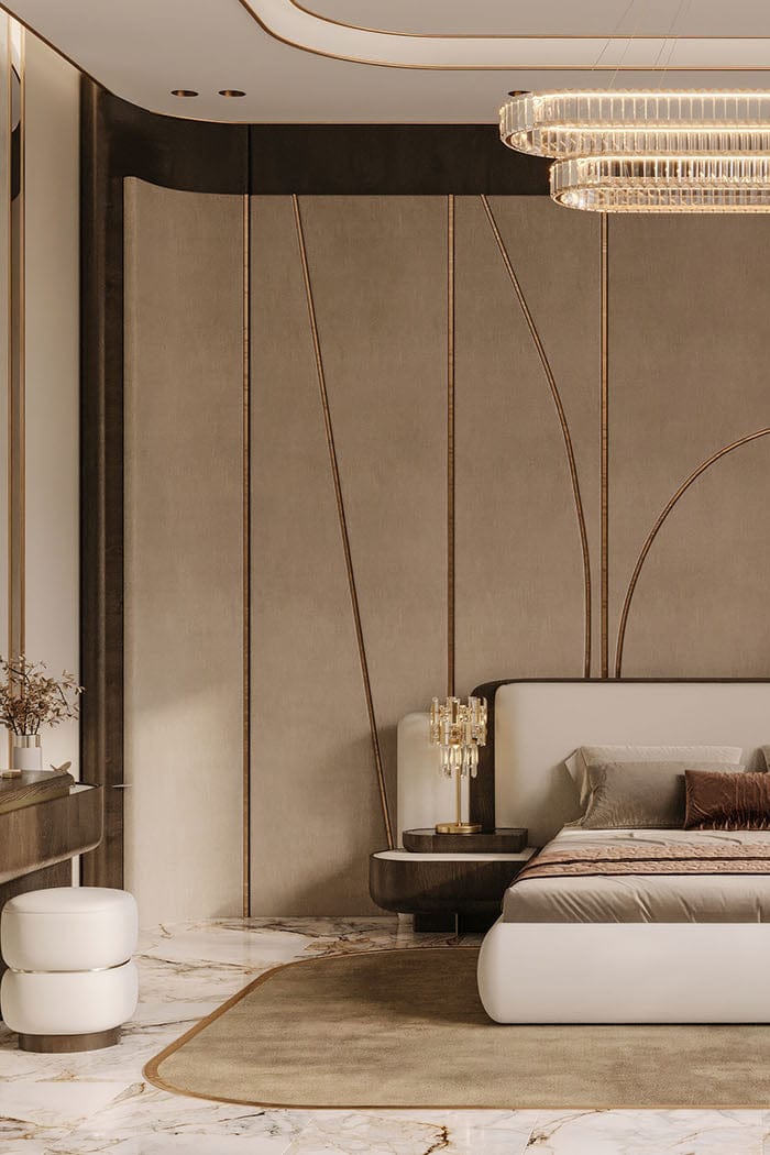 A luxury modern bedroom featuring a low-profile platform bed with a light beige upholstered headboard, styled with neutral-toned bedding. The room has a dramatic curved wall with gold-toned vertical lines, a double-tiered rectangular chandelier, a round accent chair, and marble flooring.