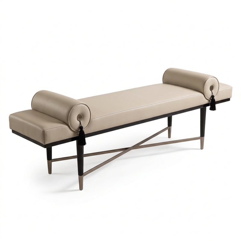 A modern upholstered bench with cream leather seating and cylindrical rolled arms, set against the foot of a bed in a styled bedroom. The bed features white linens, black textured pillows, and a dark faux-fur throw blanket.