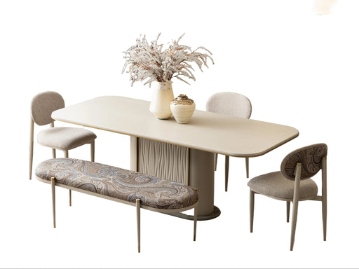 A modern dining room set featuring a light beige oval table with a textured pedestal base, four upholstered dining chairs in neutral tones, a matching patterned upholstered bench, and decorative ceramic vases on the table.